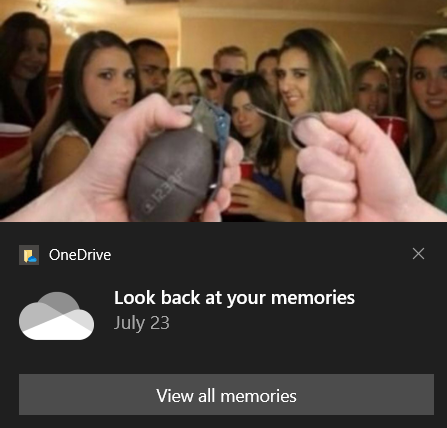 Point of view of someone pulling the pin out of a grenade at a crowded party. The image is from a notification from OneDrive titled 'Look back at your memories'.